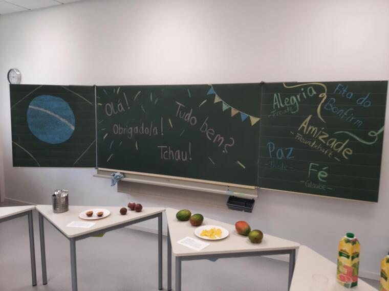 Man sieht Tische, auf denen Obst aus Südamerika liegt. Außerdem ist auf der Tafel im Hintergrund die brasilianische Flagge zu sehen und verschiedene Wörter sind auf die Tafel geschrieben