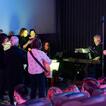 Man sieht die Band, ca. 10 Personen, die Musik machen