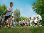 Man sieht Kinder bei Sonnenschein über eine Wiese laufen 