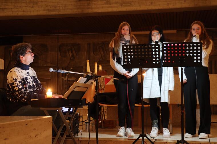 Ein Mann sitzt am Klavier, 3 Personen singen 